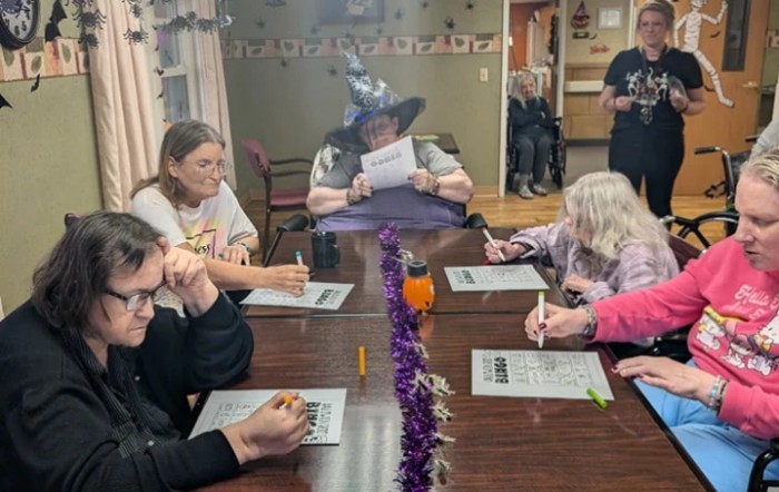 A group of people engaging in a Halloween-themed activity around a table.