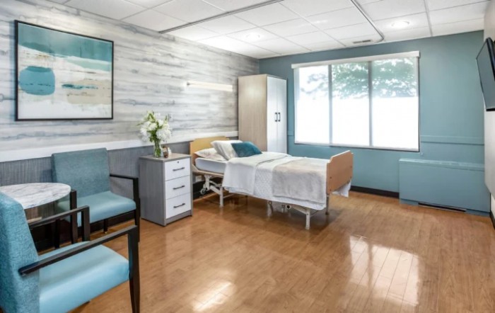 A clean and well-organized hospital room with a single bed and large windows.