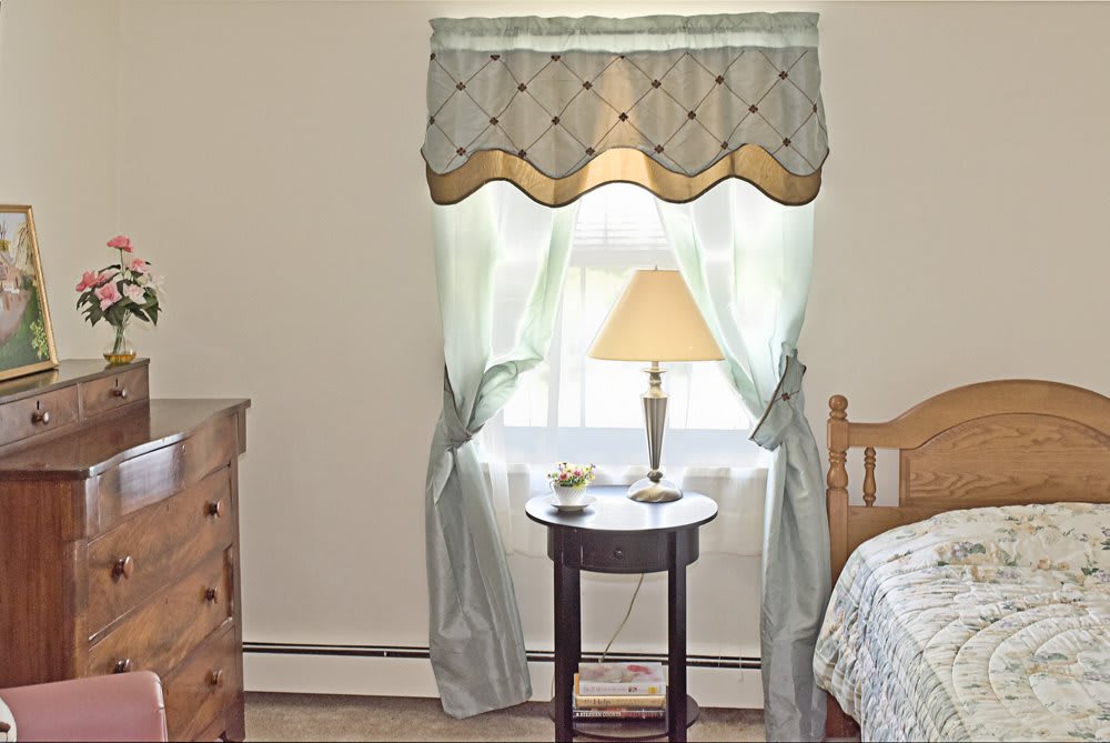 A cozy bedroom with a lamp on a small round table by the window.