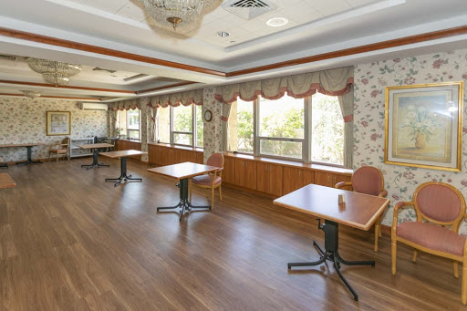 An empty restaurant interior featuring tables arranged near large windows, allowing for natural light to fill the space.