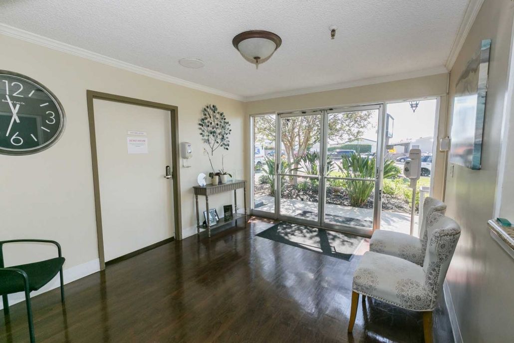 A bright entryway with hardwood flooring and large glass doors leading outside, adorned with decorative items on a side table.