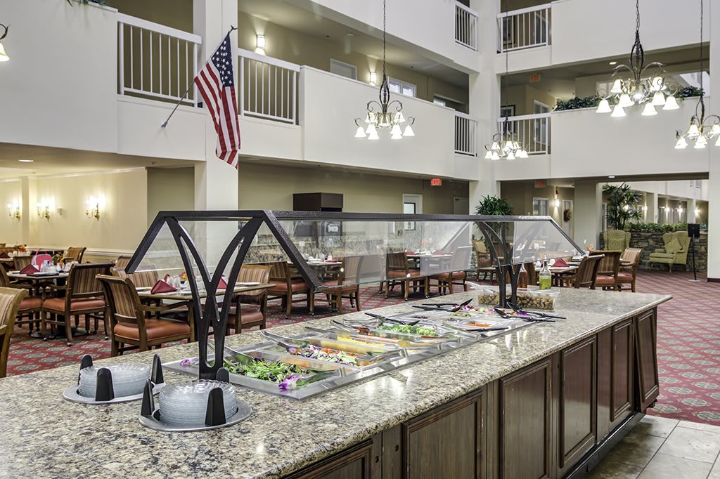 A well-lit indoor buffet area with a salad bar, featuring an American flag in the background.