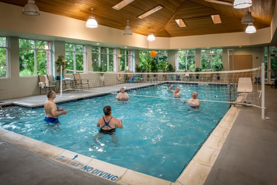A group of people playing a game in an indoor swimming pool.