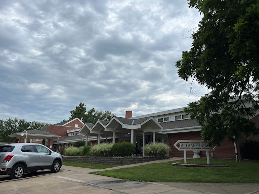 A residential building under a cloudy sky with a parked car.