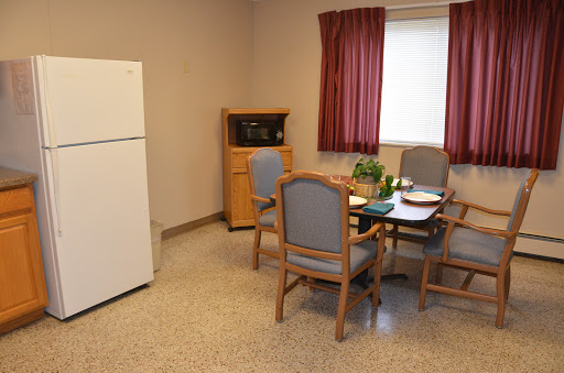 A cozy kitchen and dining area featuring a refrigerator, microwave, and a small table set for meals.
