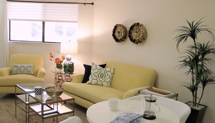 A cozy living room with a yellow sofa, decorative pillows, and wall art.