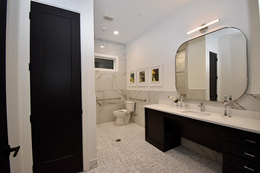 A sleek and modern bathroom featuring marble walls, contemporary fixtures, and stylish lighting.