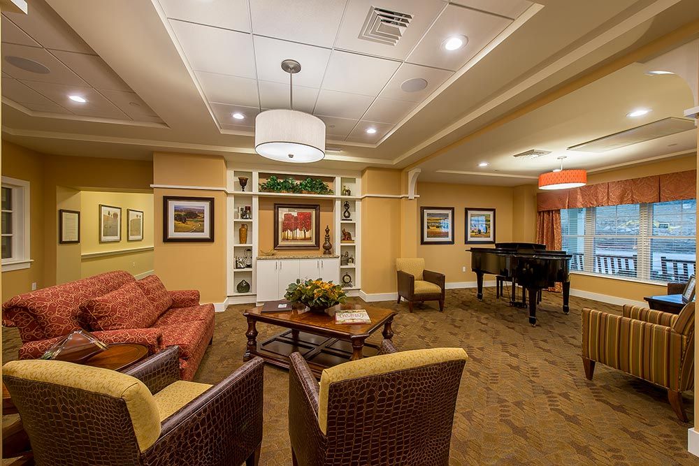 A cozy lounge area featuring comfortable seating, a piano, and decorative artwork.