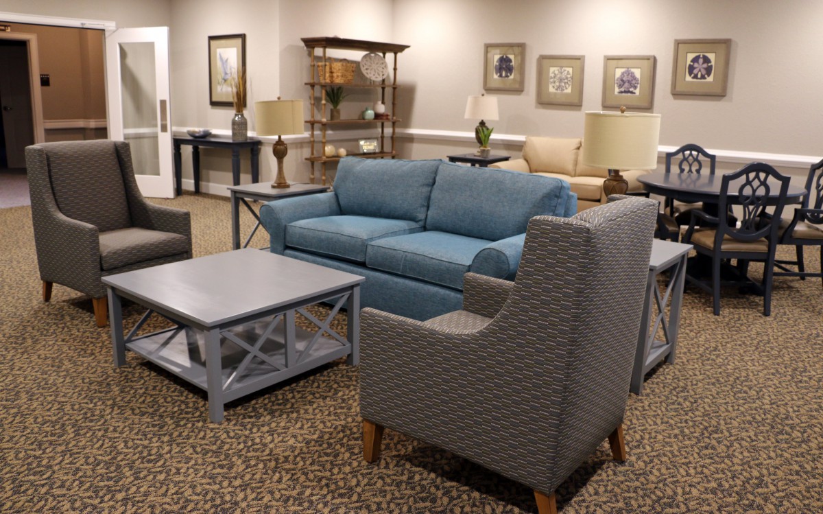 A cozy living room with modern furnishings, featuring a blue sofa, patterned armchair, and stylish coffee table.