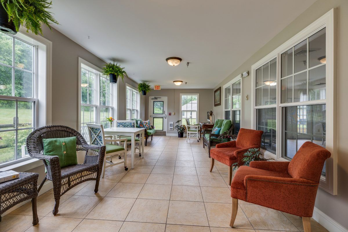 A bright and inviting sunroom with various seating arrangements, large windows, and decorative plants.