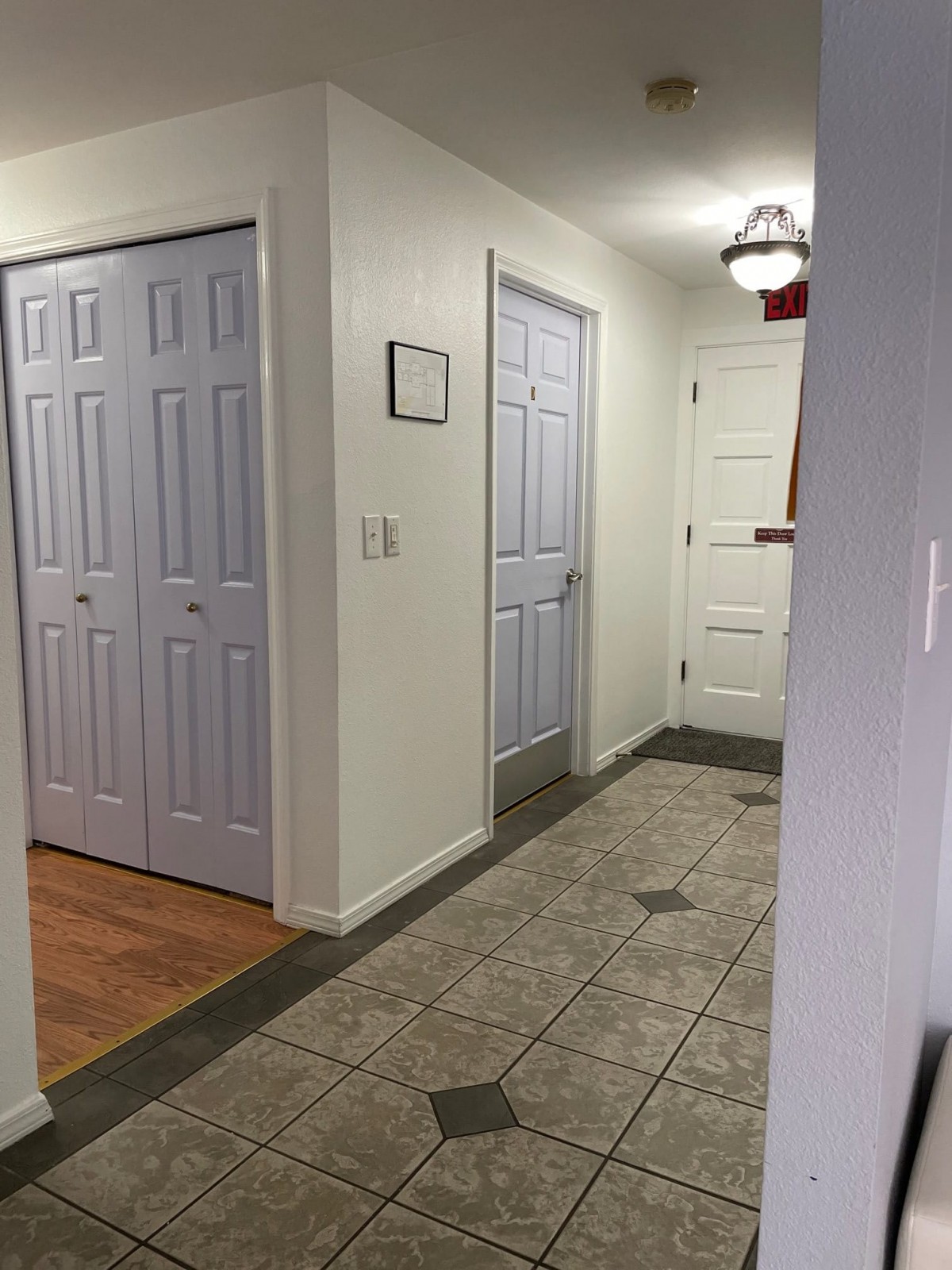A hallway with tile flooring and several closed doors.