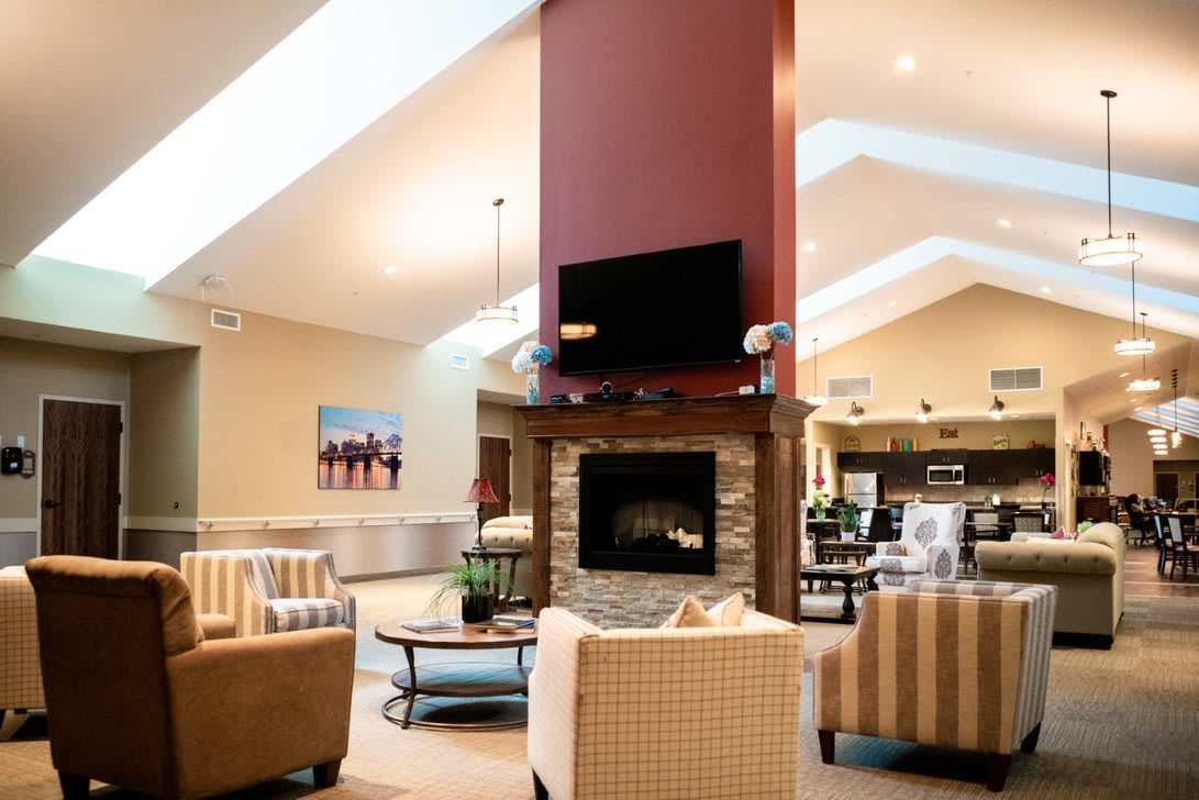 A modern living room with a central fireplace, skylights, and comfortable seating.