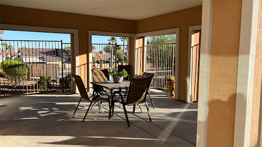 A cozy outdoor patio area with a table and chairs, bathed in warm sunlight.
