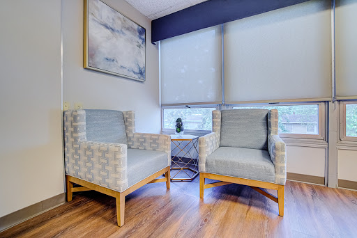A cozy seating area featuring two modern chairs and a piece of artwork on the wall.
