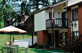 A suburban house with a balcony and outdoor seating area in the yard.