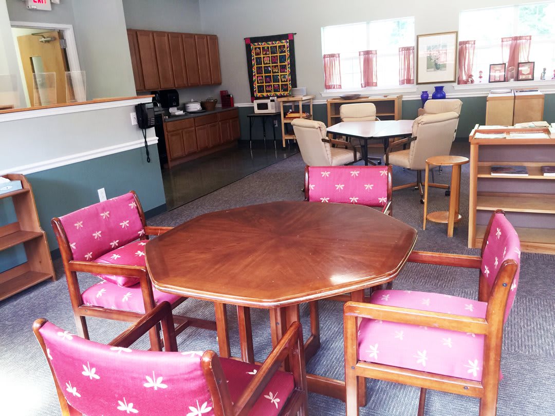 A community room with tables and chairs arranged for small gatherings.
