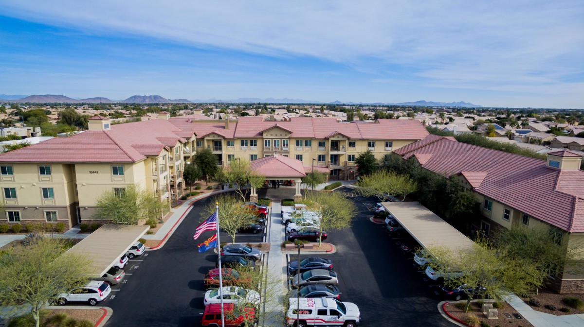 Aerial view of a large building complex with a parking lot and flags at the entrance.