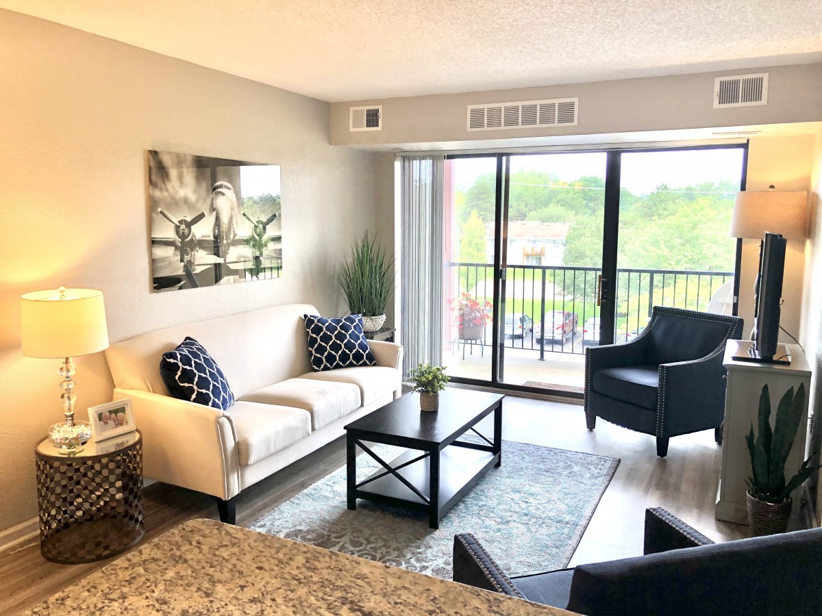 A modern living room with a comfortable sofa and armchairs, featuring a large window with a view.