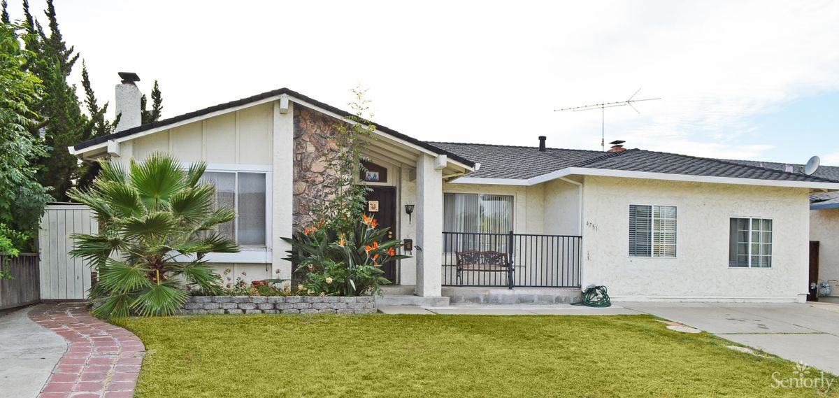 A suburban house with a well-maintained front lawn and stone facade.