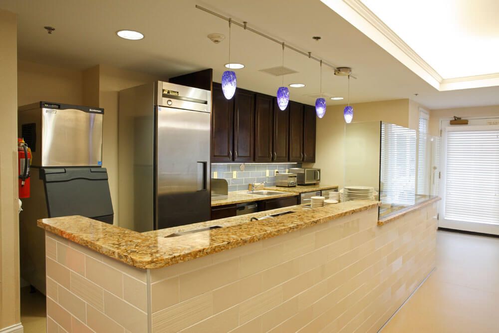 A modern kitchen with a granite countertop, stainless steel appliances, and stylish pendant lighting.