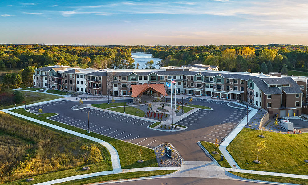 Aerial view of a large building complex surrounded by a parking lot and scenic landscape.