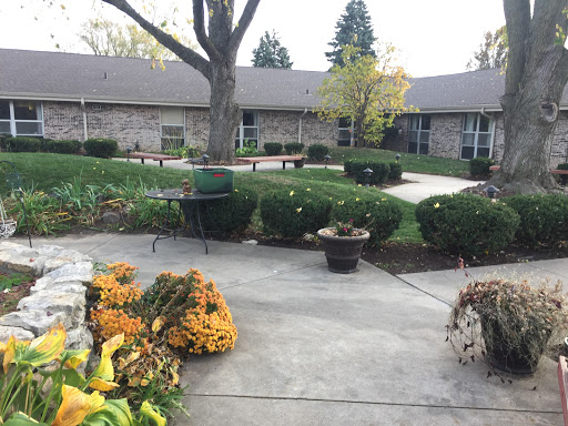 A serene courtyard surrounded by neatly trimmed bushes and blooming flowers, offering a peaceful outdoor space.