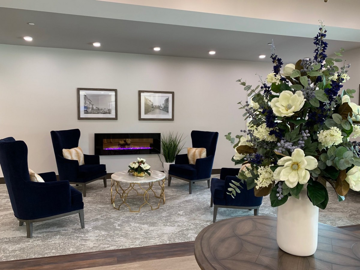 A modern living room with elegant seating, a decorative fireplace, and a bouquet of flowers.