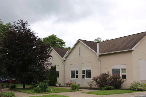 A view of a modern residential building surrounded by trees and a cloudy sky.