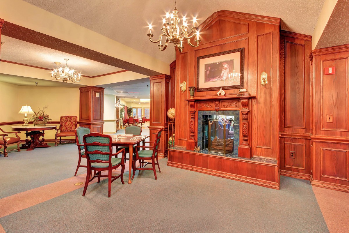 A cozy, traditionally designed room featuring a wooden fireplace and elegant furniture.