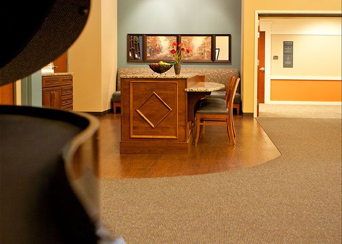 A warmly lit reception area with a desk and chairs, complemented by artwork on the wall.
