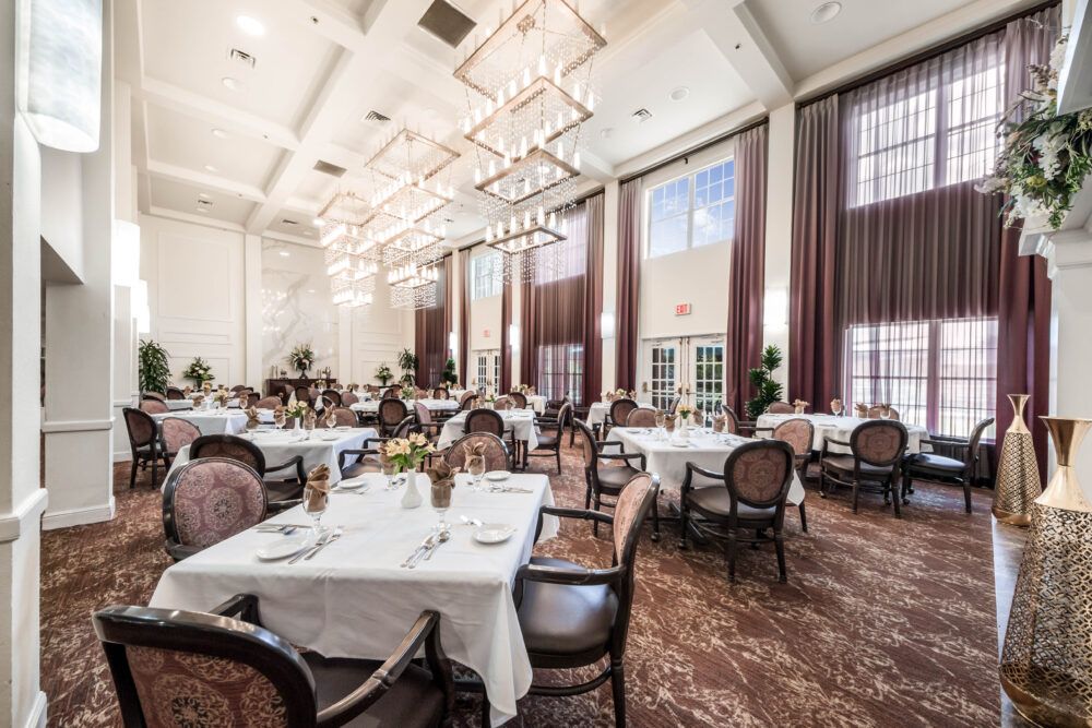 A spacious and elegantly decorated banquet hall with white tablecloths and chandeliers.