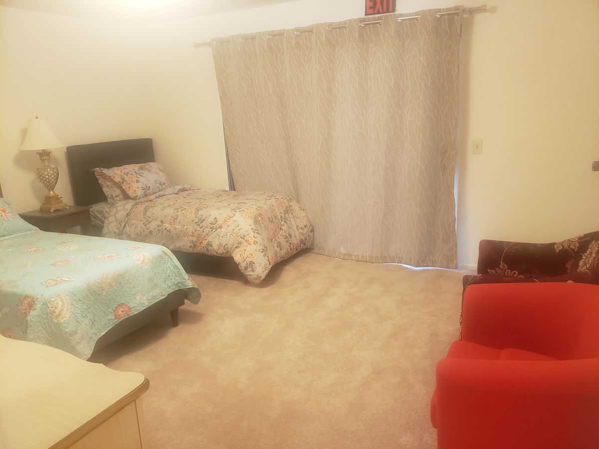 A cozy bedroom with a bed, curtains, and a red chair.