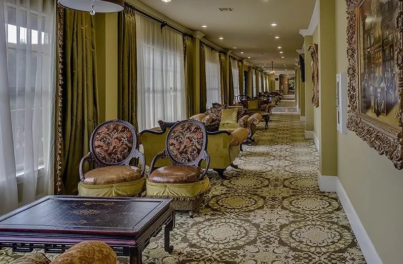 A luxurious hotel corridor featuring elegant seating arrangements and ornate decor.