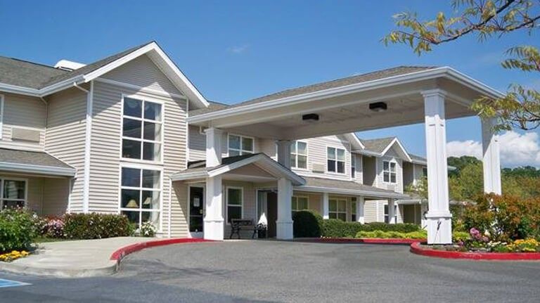 A modern residential building with a covered entrance and landscaped surroundings.