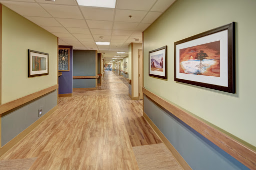A well-lit interior hallway featuring artwork on the walls and wooden flooring.