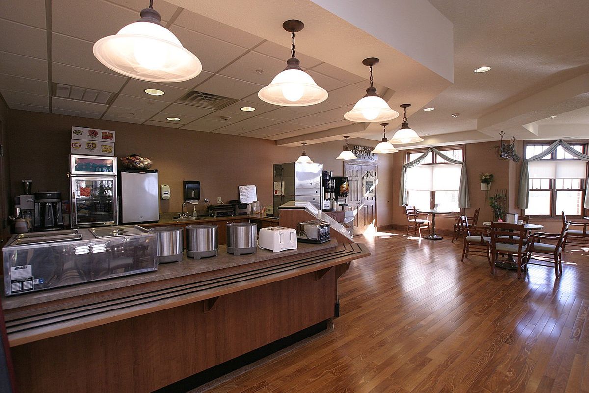 An empty cafeteria with wooden flooring and hanging lights.