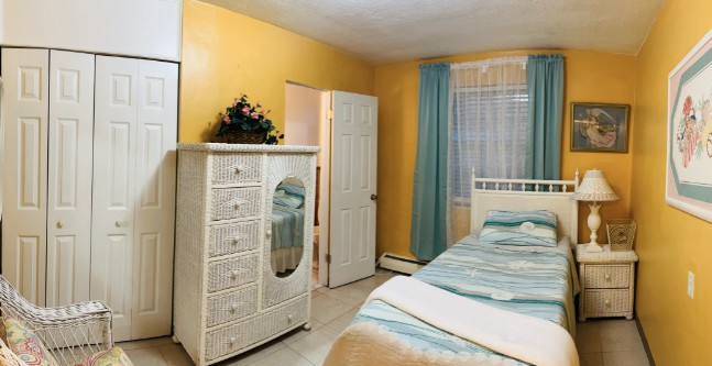 A cozy bedroom with yellow walls and a white dresser.