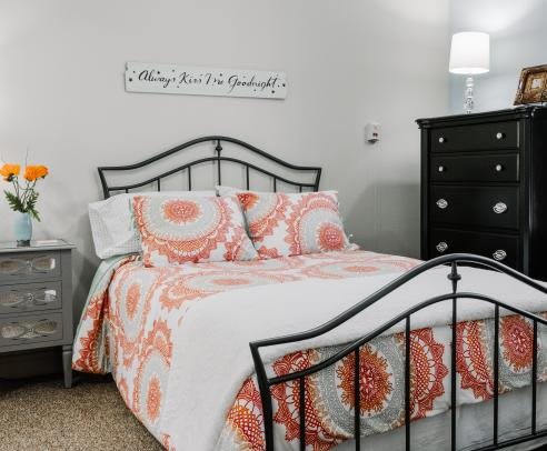 A cozy bedroom with a patterned bedspread and elegant metal bed frame.