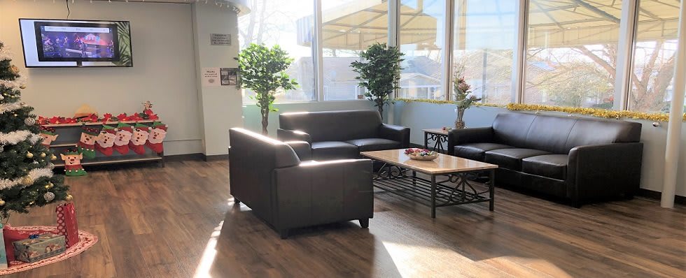 A cozy waiting area with sofas and a coffee table, illuminated by natural sunlight.