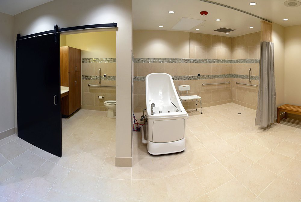 An accessible bathroom in a medical facility, equipped with a specialized bathtub and other necessary amenities.