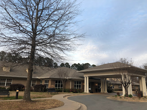 A care facility surrounded by trees under a cloudy sky.