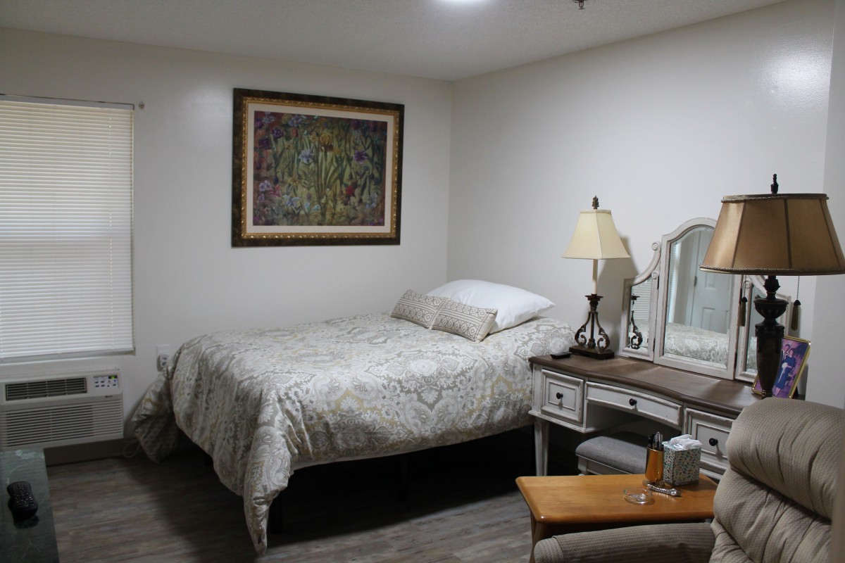 A cozy bedroom with a bed, mirror, and lamp.