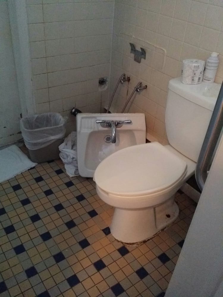 A bathroom with a toilet, detached sink, and tiled floor.