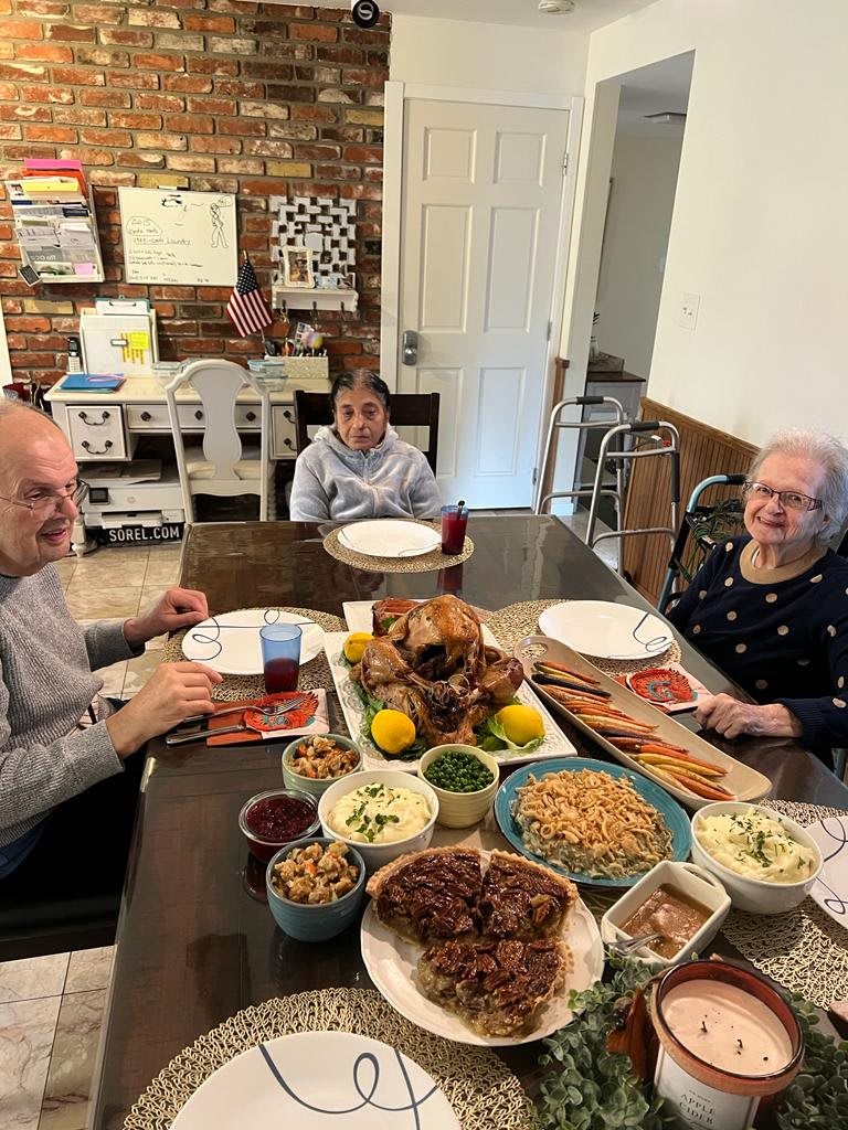 A family enjoys a meal together around the dining table, with a variety of dishes prepared for a celebration.