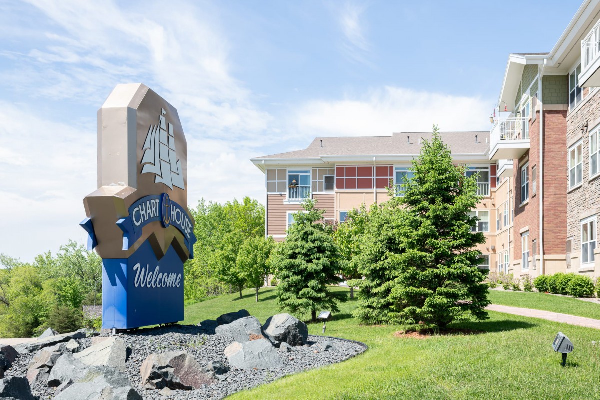 Welcome sign in front of a building surrounded by greenery and trees.