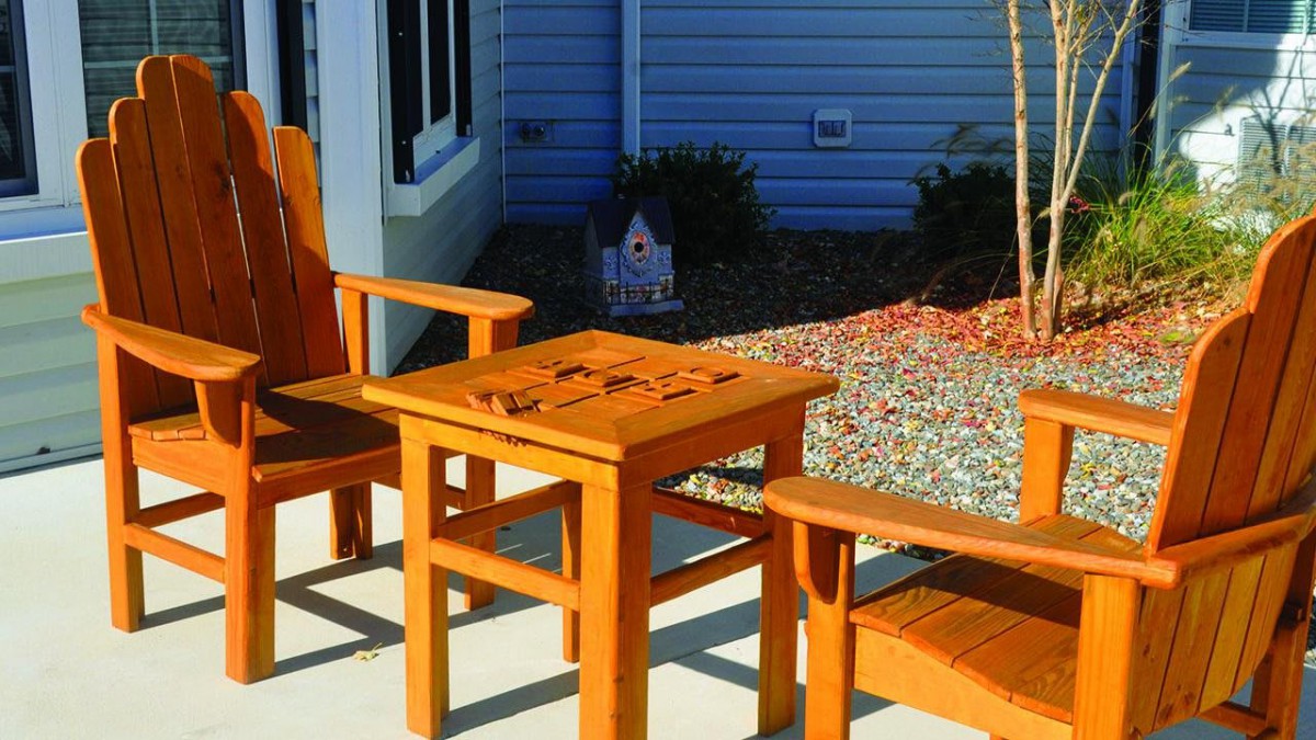 Wooden outdoor chairs and table set in a sunny patio area.