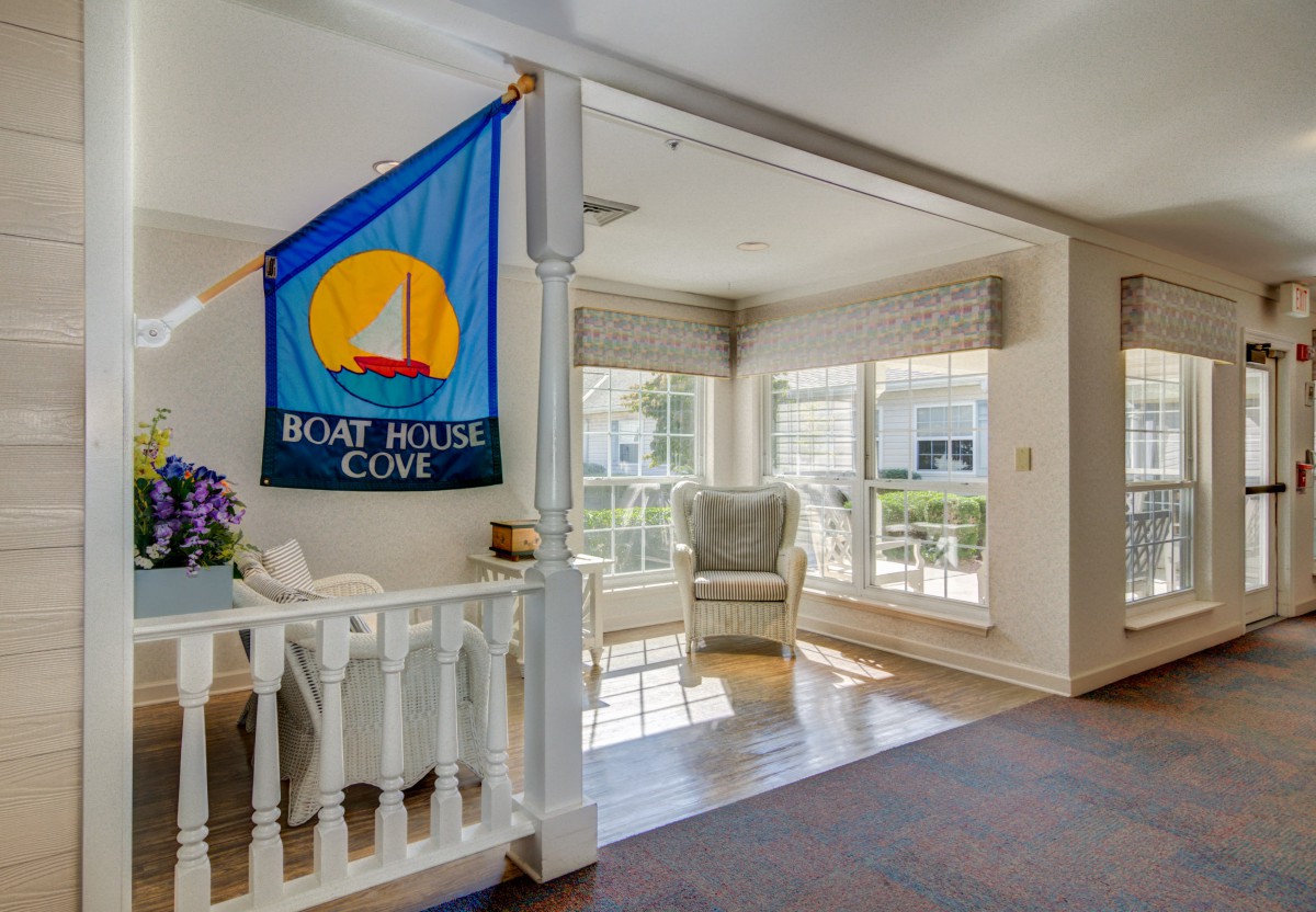 A bright, well-lit living room featuring a nautical-themed flag and cozy seating by large windows.