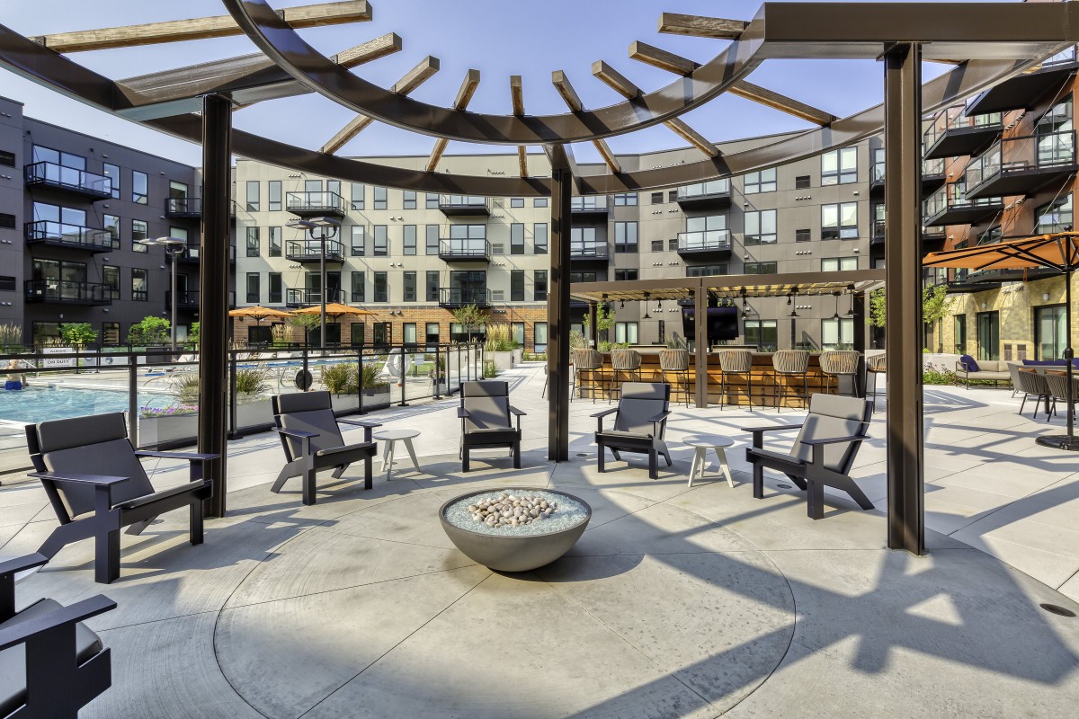 Modern outdoor seating area with a fire pit at an apartment complex.