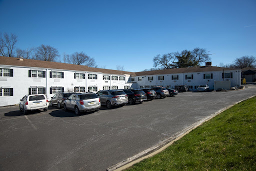 A view of a residential building with a parking lot filled with cars under a clear blue sky.