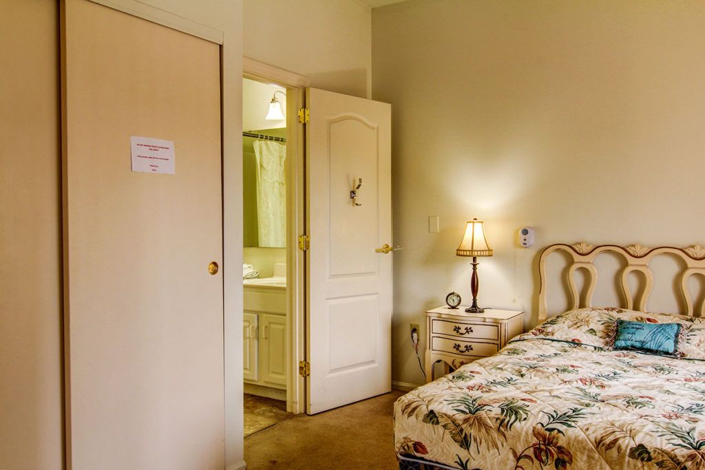 A cozy bedroom with floral bedding and a warmly lit lamp on the nightstand.